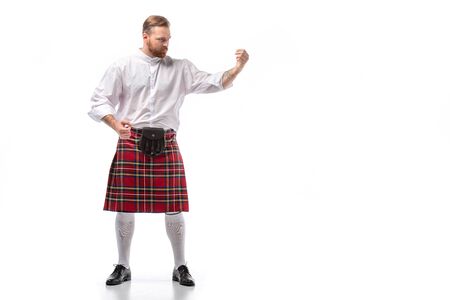 serious Scottish redhead man in red kilt on white backgroundの写真素材