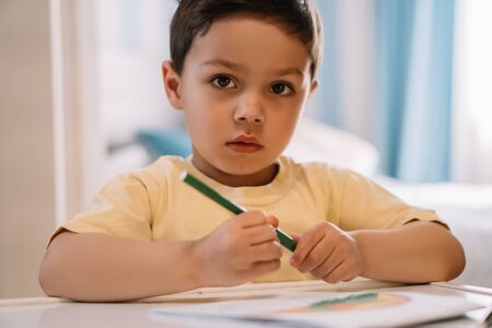 cute kid looking at camera while holding felt-tip pen