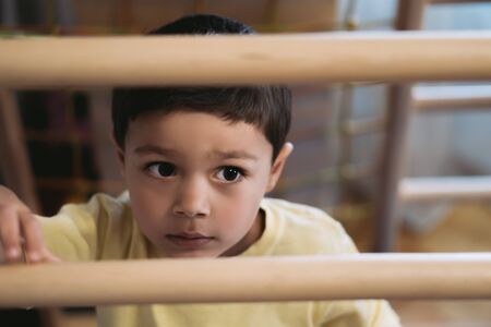 selective focus of cute boy climbing on ladder in home gym
