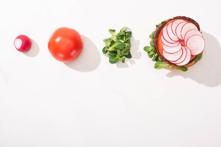 top view of vegan burger with radish, tomato and sprouts on white backgroundの写真素材