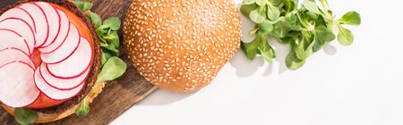 top view of vegan burger with microgreens, radish on wooden cutting board on white background, panoramic shotの写真素材