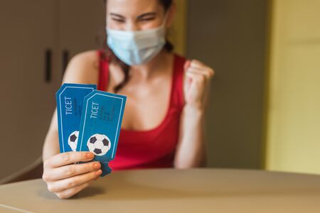 selective focus of happy woman in medical mask holding sport match ticketsの写真素材