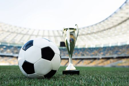soccer ball and trophy on grassy football pitch at stadiumの写真素材