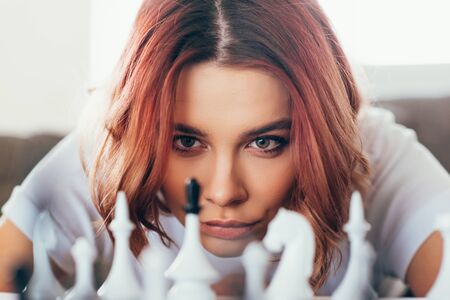 concentrated beautiful girl playing chess on self isolation, selective focusの写真素材