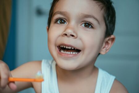 selective focus of cheerful boy holding toothbrush with toothpasteの写真素材
