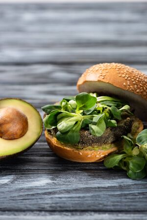 tasty vegan burger with microgreens served on wooden table with avocado halfの写真素材