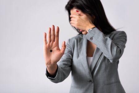 selective focus of businesswoman with black dot on palm covering face isolated on white, domestic...