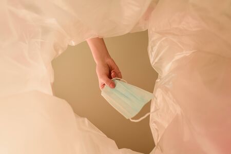 cropped view of woman throwing medical mask in trash can, end of quarantine concept
