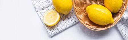 top view of ripe lemons in wicker basket on white background with dotted napkin, horizontal imageの写真素材