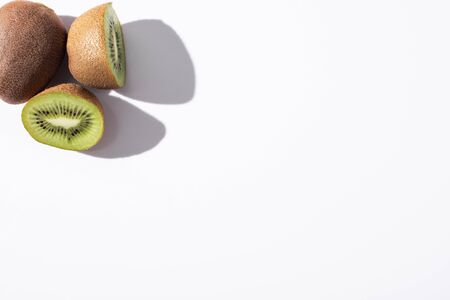 top view of whole kiwi fruit near halves on white with copy spaceの写真素材