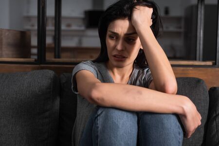 sad woman with bruise on face sitting on sofa, domestic violence conceptの写真素材