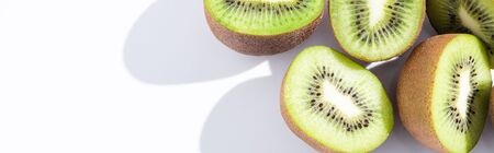 panoramic crop of fresh and ripe kiwifruit halves on whiteの写真素材