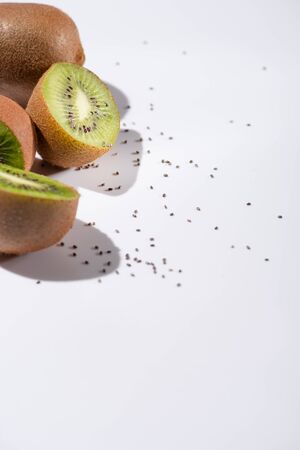 selective focus of kiwi fruit halves near black seeds on whiteの写真素材