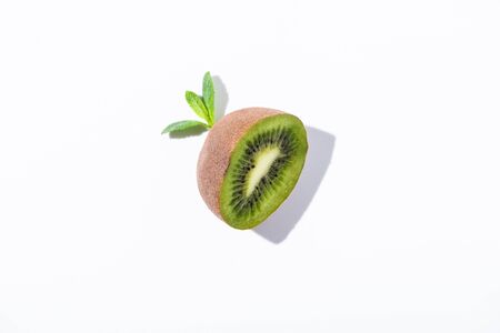top view of organic kiwi fruit half near peppermint leaves on whiteの写真素材