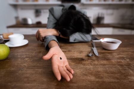 selective focus of businesswoman showing hand with black dot on palm while covering face, domestic violence conceptの写真素材