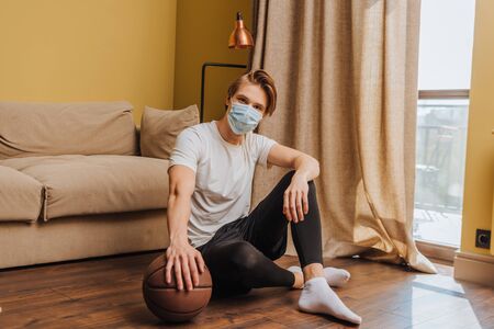 man in medical mask sitting on floor with basketballの写真素材
