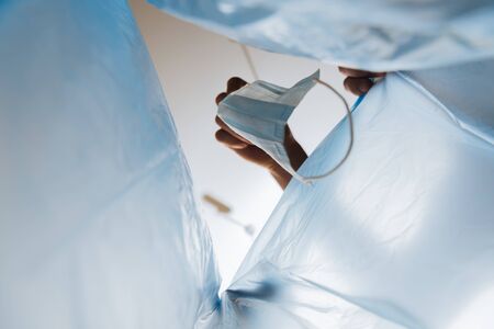 bottom view of man throwing medical mask in garbage bag, end of quarantine concept