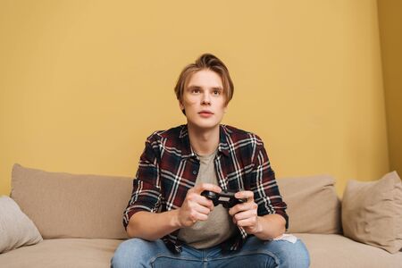 KYIV, UKRAINE - APRIL 24, 2020: handsome man holding joystick while playing video game in living...