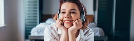smiling girl listening music with headphones at home during quarantine, panoramic conceptの写真素材