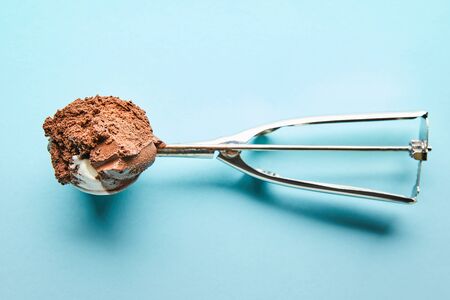 top view of fresh tasty chocolate ice cream ball in scoop on blue backgroundの写真素材