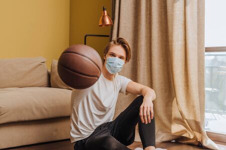 selective focus of man in medical mask holding basketballの写真素材