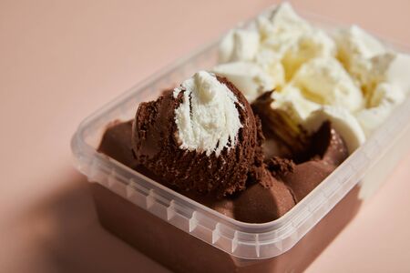 selective focus of tasty brown and white ice cream in plastic container on pink backgroundの写真素材