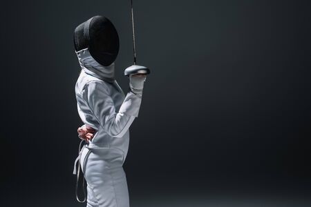 Side view of fencer holding rapier isolated on black with copy space