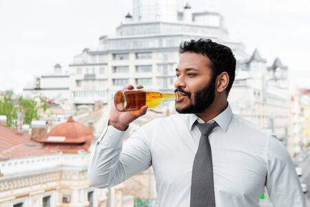 bearded african american man in medical mask drinking beer outsideの写真素材