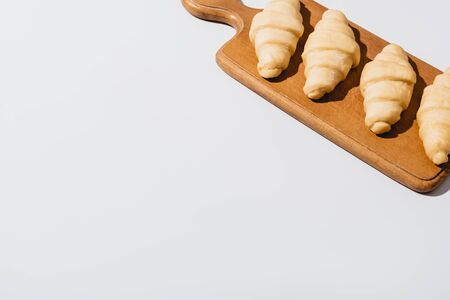 fresh raw croissants on wooden cutting board on white backgroundの写真素材