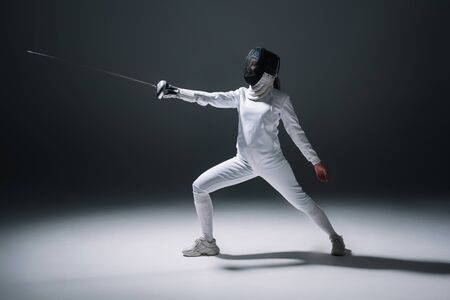 Fencer training with rapier on white surface on black backgroundの写真素材