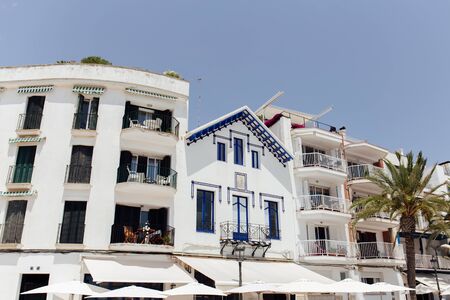 White umbrellas near facades of houses with clear sky at background, Catalonia, Spainの写真素材