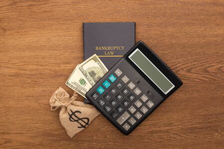top view of bankruptcy law book, cash and money bag, calculator on wooden backgroundの写真素材