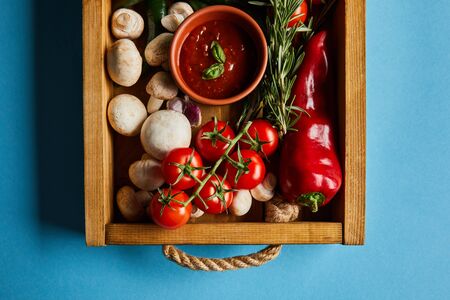 top view of tomato sauce in bowl on mushrooms near red cherry tomatoes, rosemary and chili pepper in...