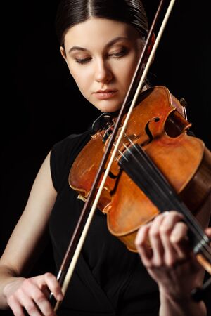 beautiful professional musician playing symphony on violin isolated on blackの写真素材