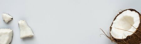 top view of fresh tasty coconut half and cracked pieces on white background, panoramic shot
