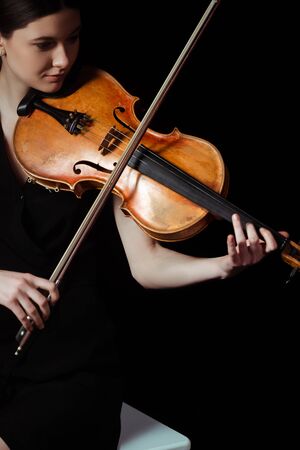 attractive female musician playing on violin on dark stageの写真素材