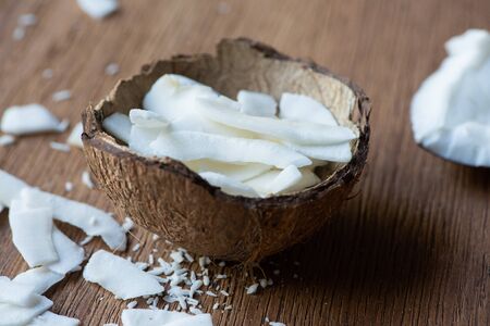 selective focus of fresh tasty coconut flakes in shell on wooden tableの写真素材