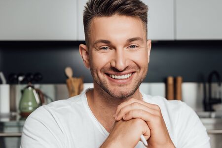 happy man with clenched hands smiling and looking at camera