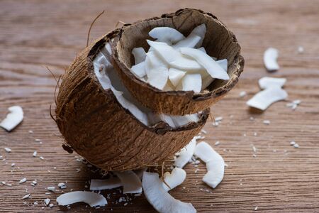 selective focus of fresh tasty coconut half and flakes in shell on wooden tableの写真素材