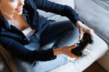 cropped view of happy woman holding joystick while playing video game in living roomの写真素材