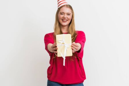selective focus of happy woman in party cap holding gift box isolated on white