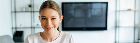 panoramic crop of cheerful woman looking at camera