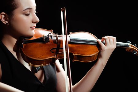 attractive female musician playing symphony on violin isolated on blackの写真素材