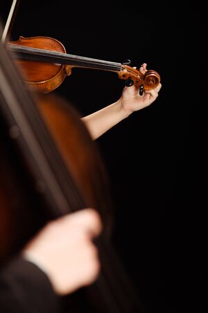 partial view of professional musicians playing on musical instruments on dark stage, selective focusの写真素材