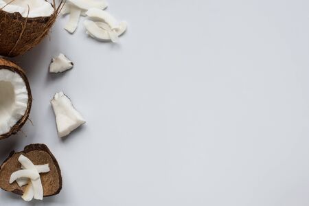 top view of fresh tasty coconut halves with cracked shell and flakes on white backgroundの写真素材
