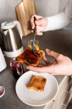cropped view of man spreading jam on toast for breakfastの写真素材