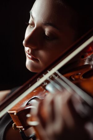 beautiful professional musician playing symphony on violin isolated on black, selective focusの写真素材