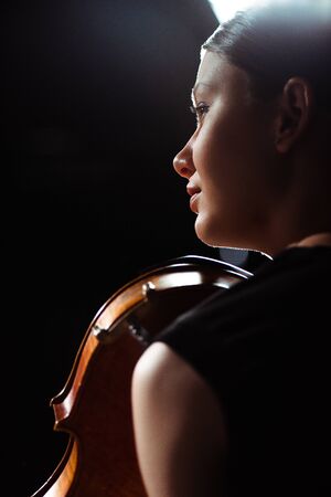 beautiful female musician playing on violin on dark stageの写真素材