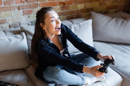 KYIV, UKRAINE - APRIL 29, 2020: excited woman holding joystick while playing video game in living...