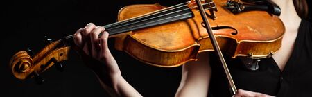 partial view of female musician playing on violin isolated on black, horizontal imageの写真素材